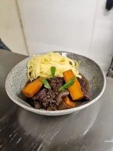 Assiette de fondant de bœuf façon bourguignonne et tagliatelles fraîches maison, servie à l’Auberge Jean le Dindon à Chaudeyrolles